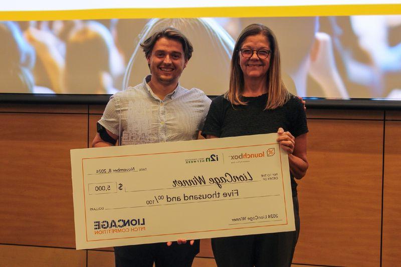 man and woman holding large checks