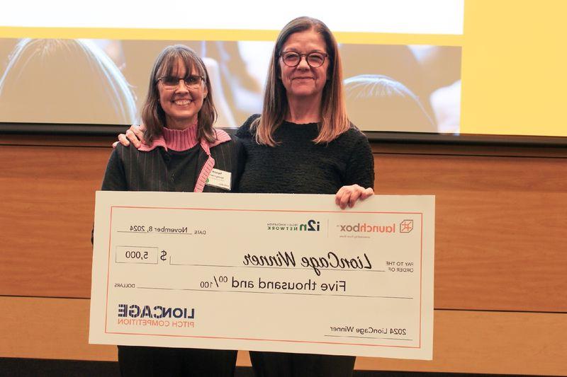 two women holding checks