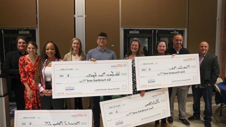 group of people holding large checks